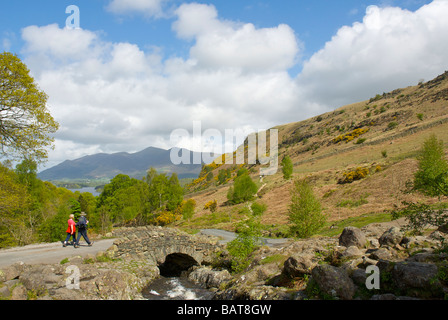 Deux promeneurs passant Ashness Pont, donnant sur Skiddaw et Derwent Water, Parc National de Lake District, Cumbria, EnglandUK Banque D'Images