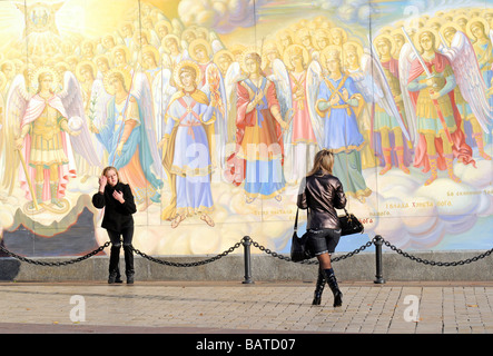 Deux femmes ukrainiennes à la mode en cuir noir habillé en posant devant une peinture murale religieuse au Monastère Saint Michel, Kiev. Banque D'Images