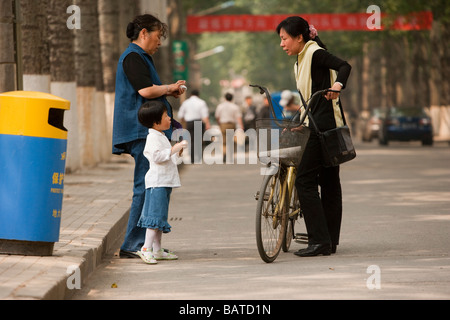 Beijing, Chine une femme et sa fille, parlez-en à un ami avec son vélo dans la rue dans un campus universitaire. Banque D'Images