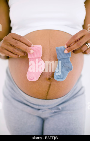 Pregnant woman holding a bleu et un bébé rose's boot, ne sachant pas si le bébé est un garçon ou une fille. Banque D'Images