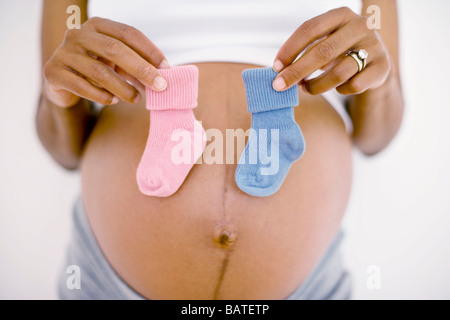 Pregnant woman holding a bleu et un bébé rose's boot, ne sachant pas si le bébé est un garçon ou une fille. Banque D'Images