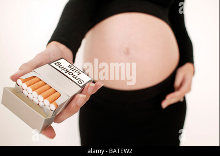 Fumer pendant la grossesse. Pregnant woman holding d'un paquet de cigarettes. Elle en est à son troisième trimestre Banque D'Images