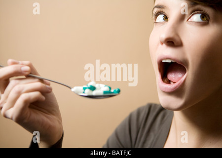 Jeune Femme prenant une cuillère pleine de comprimés Banque D'Images