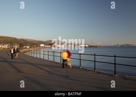 Couples marchant le soir sous le soleil sur la promenade de la ville balnéaire de Largs dans le nord Ayrshire sur la côte ouest de l'Écosse, Royaume-Uni Banque D'Images