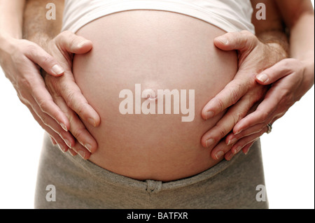 Les futurs parents. Femme enceinte et son partenaire reposant les mains sur son abdomen gonflé. Elle en est à son troisième trimestre. Banque D'Images