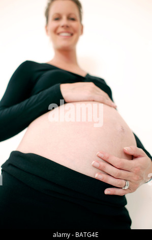 Pregnant woman holding her abdomen gonflé. Elle en est à son troisième trimestre. Banque D'Images