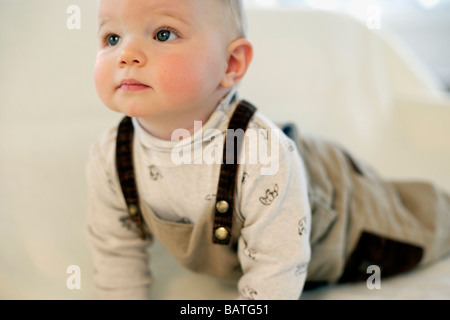 Bébé garçon allongé sur un canapé. Il est de neuf mois. Banque D'Images