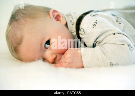 Bébé garçon allongé sur un canapé. Il est de neuf mois. Banque D'Images