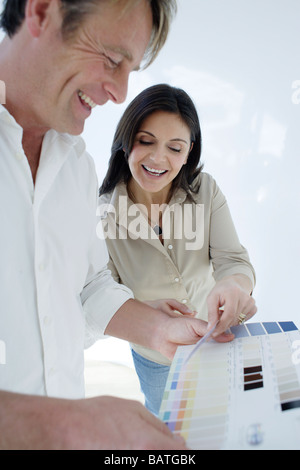 Couple heureux en choisissant parmi les échantillons de couleur à utiliser pour la décoration d'une chambre. Banque D'Images