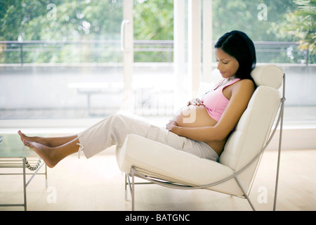 Femme enceinte se reposant dans une chaise. Elle est à terme. Banque D'Images