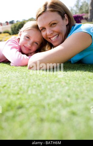 Smiling mother and daughter lying together sur le terrain. Banque D'Images