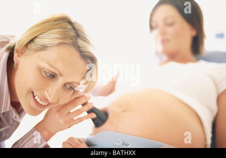 Examen obstétrique. Sage-femme(à gauche) à l'aide d'une oreille corne pressé à un pregnantwoman Banque D'Images