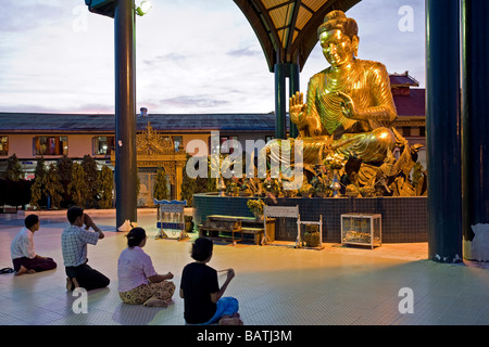 La femme priant devant grand Bouddha de bronze. Paya Botataung. Yangon. Le Myanmar. Banque D'Images