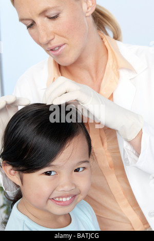 Examen des poux de tête. Médecin de la vérification d'une fillette de six ans pour les poux de tête (Pediculus humanus capitis). Banque D'Images