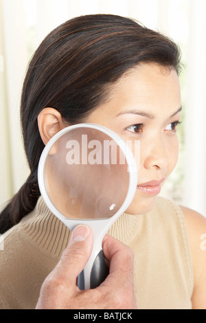 Examen dermatologique. À l'aide d'un dermatologue loupe pour examiner la peau d'un patient. Banque D'Images