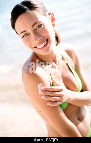 Appliquez un écran solaire pour femme hershoulder. Banque D'Images