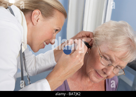 Examen de l'oreille. Médecin généraliste à l'aide d'un otoscope pour examiner les anelderly'oreille du patient. Banque D'Images