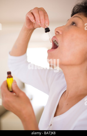 Rescue Remedy. Femme à l'aide d'une pipette pour prendre un extrait connu sous le nom de Bach Rescue Remedy. Banque D'Images