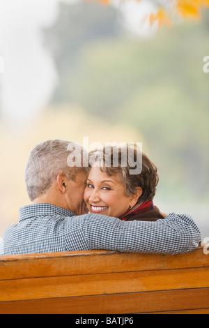 African couple hugging on park bench Banque D'Images