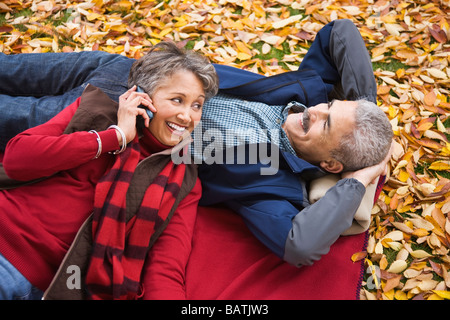 African couple laying on blanket en automne avec cell phone Banque D'Images