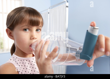 L'entretoise de l'asthme. Jeune fille à l'aide d'une entretoise en plastique (chambre) avec un inhalateur, pour traiter son asthme. Banque D'Images