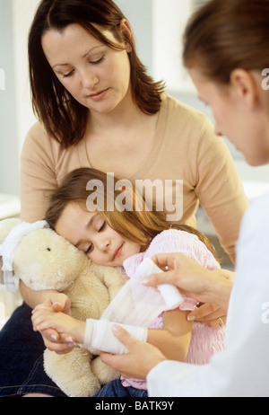 Blessure du bras. Les jeunes girlwith bandage bras être réconforté par sa mère. Banque D'Images
