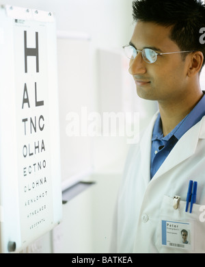 Optométriste à côté d'un eyechart. Le tableau est utilisé pour tester l'acuité visuelle. Banque D'Images