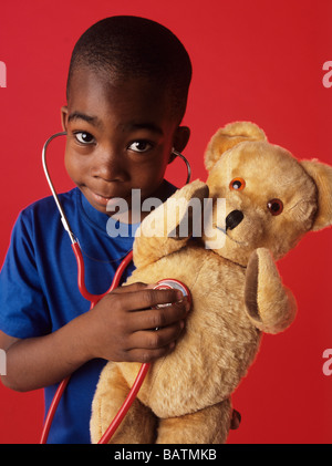 La prétention de l'examen. Garçon de 6 ans à l'écoute de son ours en peluche à l'aide de la pulsation d'un stéthoscope. Banque D'Images