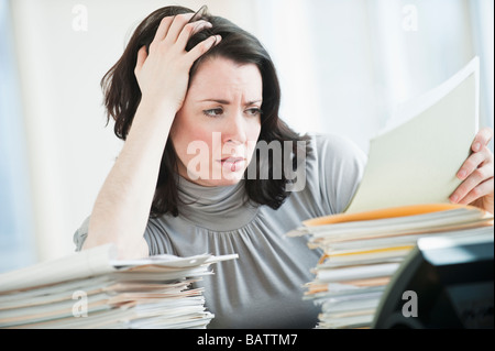 Stressed business woman reading paperwork in office Banque D'Images