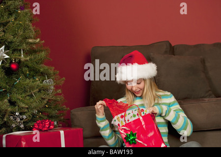 Teenage girl (14-15) wearing Santa hat opening Christmas Gift Banque D'Images