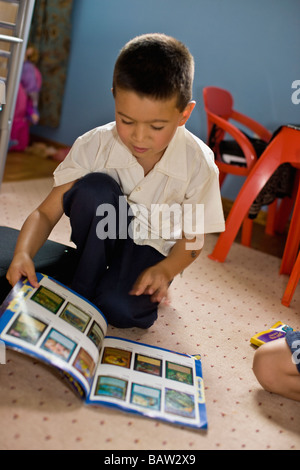 Asian boy reading magazine dans la chambre Banque D'Images