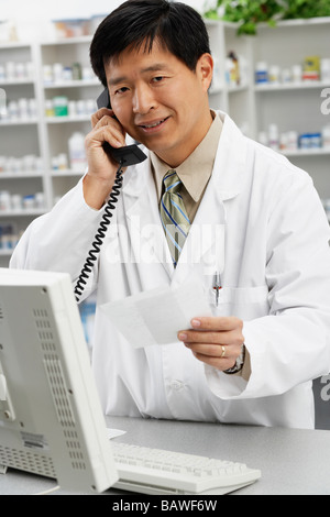 Asian male pharmacien talking on telephone Banque D'Images