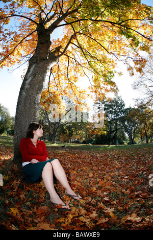 Une jeune femme portant une jupe se trouve dans un parc pendant la saison d'automne à Victoria, BC, Canada. Banque D'Images