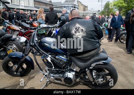 Grand homme assis sur custom moto dans Pavilion Gardens Buxton Derbyshire dans le Peak District en Angleterre UK Banque D'Images