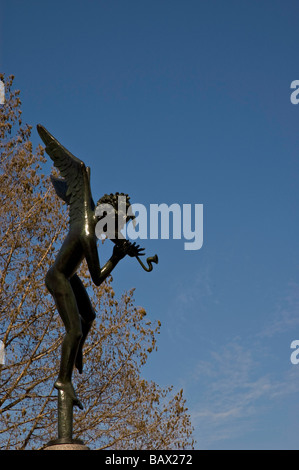 Angel scuplture sur piédestal dans les arbres avec un ciel presque sans nuages bleu Banque D'Images