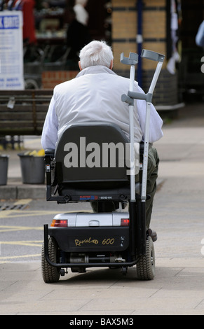 Homme conduisant un scooter de mobilité avec ses béquilles stockés sur l'arrière Banque D'Images