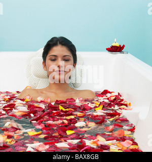 Hispanic woman in bathtub avec pétales de fleurs Banque D'Images