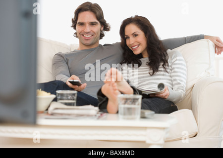 Hispanic couple watching television on sofa Banque D'Images