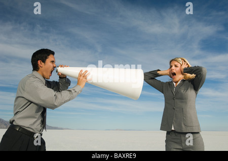 Hispanic businessman yelling at businesswoman par mégaphone Banque D'Images