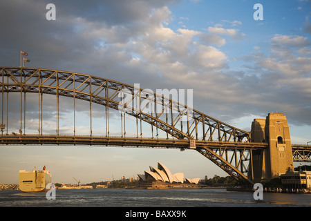 Au départ de la ville de passage de porte-conteneurs's iconic Harbour Bridge et l'Opéra de Sydney au coucher du soleil dans la Nouvelle-Galles du Sud Australie Banque D'Images