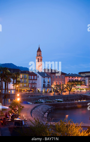 Port et promenade du port avec clocher d'église Santi Pietro Paolo en arrière-plan dans la soirée, Ascona, le Lac Majeur, Ticin Banque D'Images