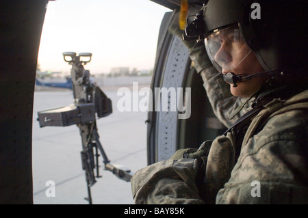 UH-60 Black Hawk mitrailleur de porte se prépare pour le décollage de LZ Washington dans la zone verte de Bagdad. Banque D'Images