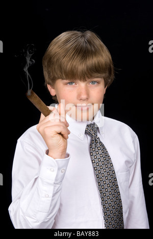 Un jeune garçon dans une chemise et cravate fume un cigare comme si vivre une vie de la haute société Banque D'Images