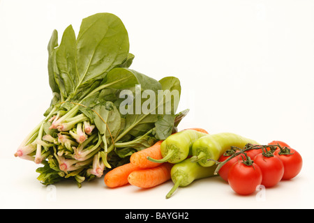 Diverses matières et des légumes frais, tomate paprika vert, la carotte et les épinards (découpe) isolé sur fond blanc. Close up. Banque D'Images
