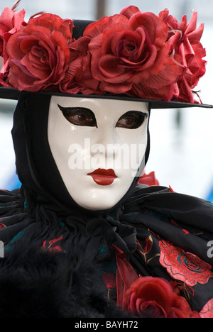 Seule fille dans un déguisement carnaval vénitien noir avec roses rouges Banque D'Images