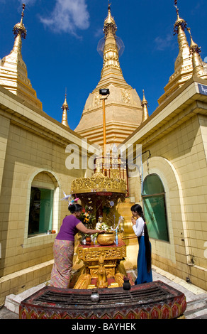 Les birmanes faire une offrande à la porte des postes. Sule Paya. Yangon. Myanmar Banque D'Images