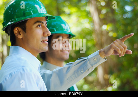 Business People in green hard hats pointant à l'extérieur Banque D'Images