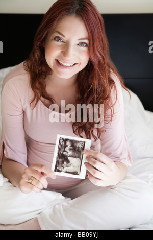 Pregnant Hispanic woman holding sonogram photo Banque D'Images