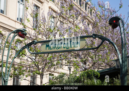 La station de métro signe en cité avec jacarandas en fleurs Banque D'Images