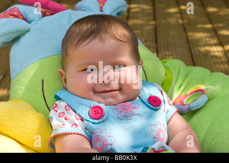 Close up portrait of horizontal d'une petite fille de six mois en haussant les épaules de rire dans le jardin sur une journée ensoleillée Banque D'Images